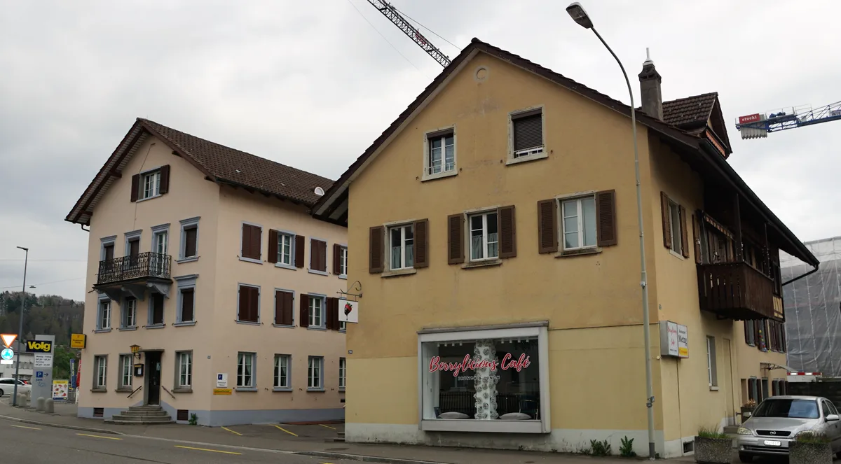 Man sieht zwei Häuser, ein rötliches und ein gelbes mit dem Restaurant Metzg und dem Café Berrylicious.